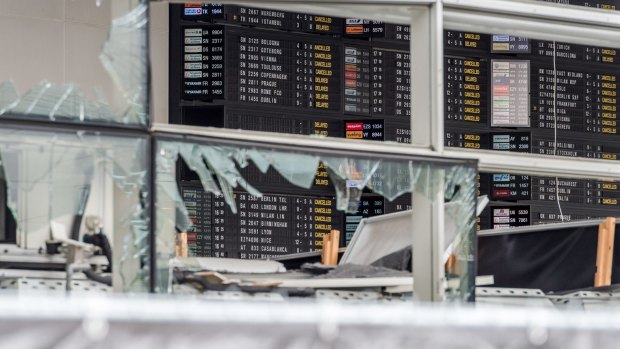 An arrivals and departure board is seen behind blown out windows at Zaventem Airport in Brussels.