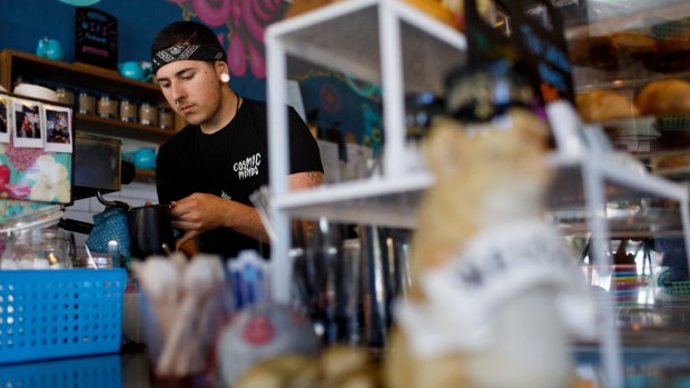 Barista Zac Jarvis working in Little Oink at the Cook shops. This buzzing cafe has thrived despite growing pressure from larger shopping precincts, while others haven't been so lucky.