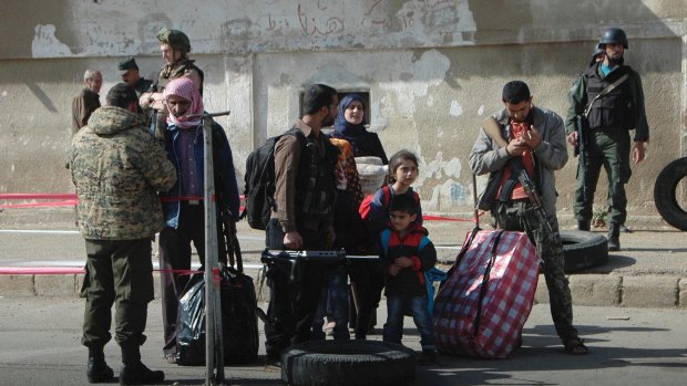 Syrian opposition fighters and their families prepare to leave al-Waer on Saturday.