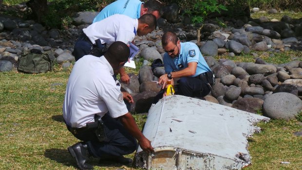 French police inspect a large piece of plane debris that was found on the beach in Saint-Andre, on Reunion Island, in July.