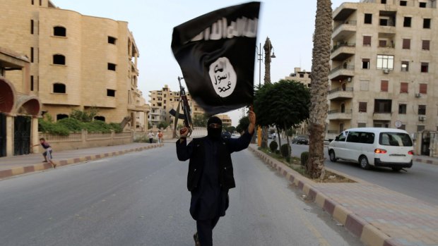 A member of Islamic State waves an IS flag in Raqqa, Syria.