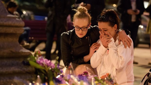 A woman is consoled as she looks at the floral tributes following an evening vigil outside the Town Hall in Manchester. 