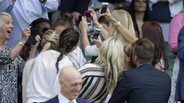 People pose for a selfie with British former soccer player David Beckham at Wimbledon.