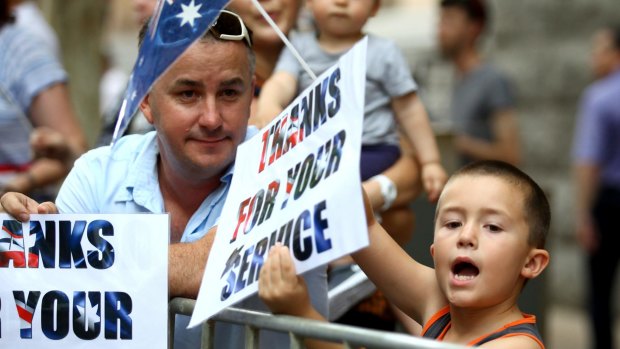 Six-year-old Lachlan Skillen and dad Shane watch almost 3000 veterans of Operation Slipper march through Brisbane's CBD on Saturday.