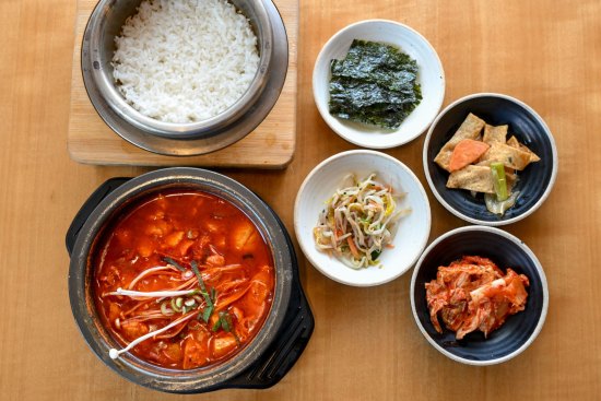 The signature tofu soup, sundubu-jjigae (bottom left), comes with banchan (snacks) and rice.