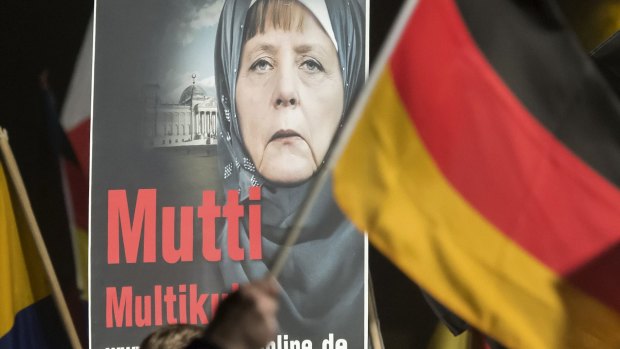 A banner reading 'Mum multiculti' and depicting a manipulated image of German Chancellor Angela Merkel is carried by a protester behind the German flag as thousands of people join a protest in Erfurt, central Germany, in October. 