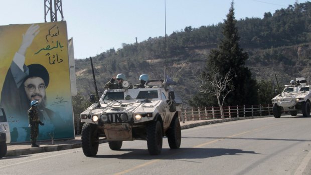 United Nations peacekeeping vehicles  drive past a picture of Hezbollah leader Hassan Nasrallah on the Lebanese side of the border with Israel.