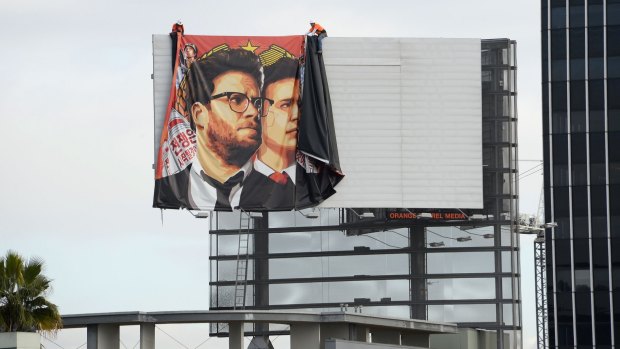 Workers remove a banner poster for <i>The Interview</i> from a Hollywood billboard.