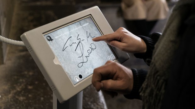A tourist uses a computer tablet in Giotto's bell tower, which allows them to leave their mark at the site digitally, in Florence, earlier this month. 