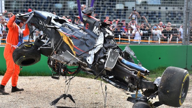 A track official assists the removal of McLaren driver Fernando Alonso's car.
