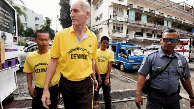 Peter Scully (second from left) arrives at the Cagayan De Oro court handcuffed to another inmate on the first day of his trial in September. 