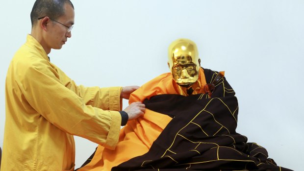 Abbot Zhen Yu places a robe on the mummified body of revered Buddhist monk Fu Hou.