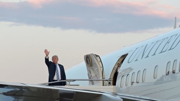 President Donald Trump waves from the top of the steps of Air Force One.