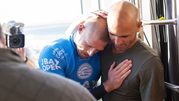 Glad you're alright: Kelly Slater embraces fellow world champion Mick Fanning.