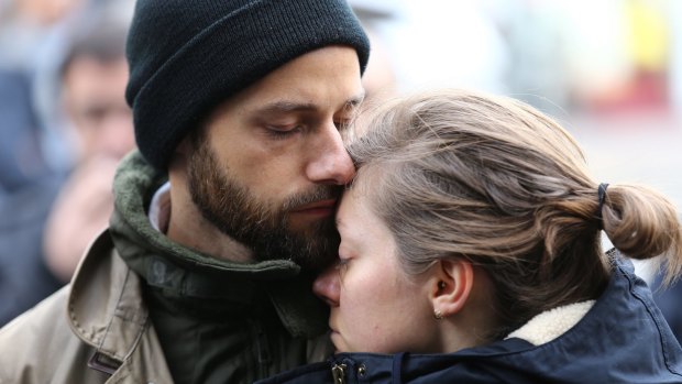 A couple embrace after laying flowers at the La Belle Equipe cafe in Paris France.