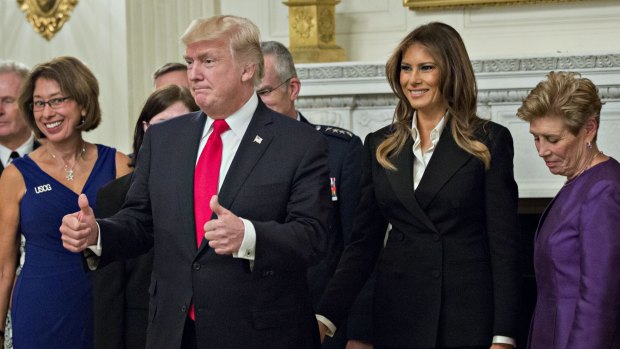 US President Donald Trump gives a thumbs up next to first lady Melania Trump during an official photograph with senior military leaders and spouses at the White House.