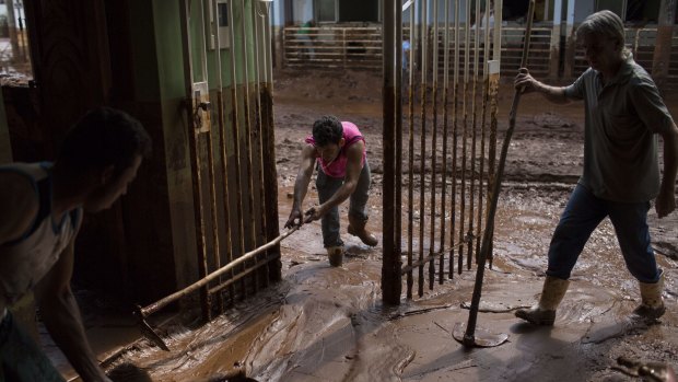 People remove mud from a damaged home in Barra Longa after a dam burst.