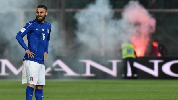 Italy's Daniele De Rossi smiles as flares rained down.
