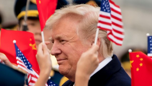 Children wave US and Chinese flags as President Donald Trump arrives at Beijing Airport.