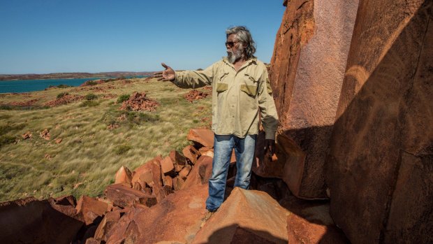 Senior cultural ranger at Murujuga National Park, Jakari Togo, looks out to sea next to rock carvings on the Burrup Peninsula.