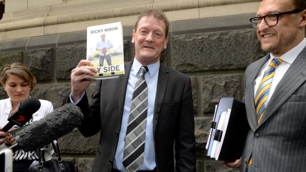 Former AFL player manager Ricky Nixon outside the Court of Appeal  with a copy of his autobiography My Side.