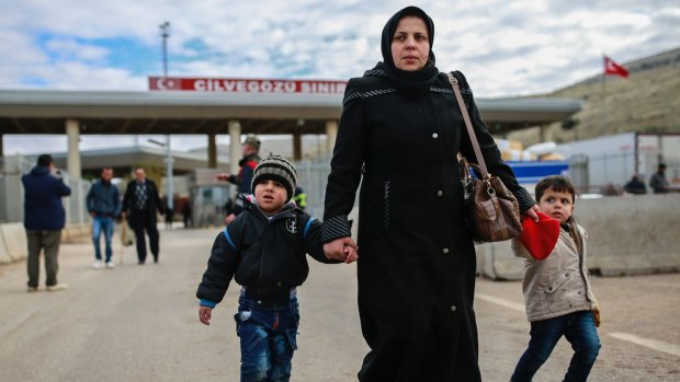 Iptisam Muhammed, 25, from Aleppo, walks with her children across the Turkish border on Sunday.