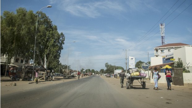 Residents walk on an empty street in Banjul. Heavy gunfire rang out on Tuesday near the presidential palace in Banjul, capital of the tiny West African nation of Gambia, residents said.