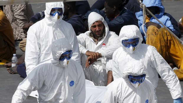 The captain sits as more bodies of migrants are taken from the Italian coastguard ship.