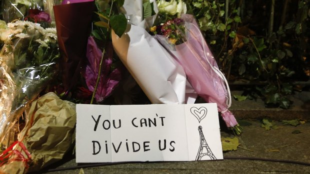 Flowers stand next to a sign near the Bataclan concert hall.