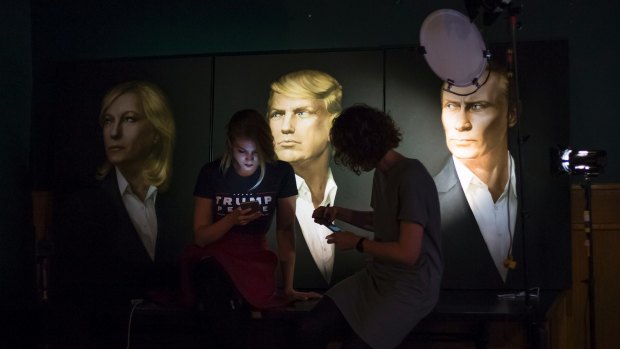 Two women wait in front of portraits of Marine Le Pen, Donald Trump and  Vladimir Putin for a live telecast of election results in a pub in Moscow.
