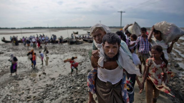 A Rohingya Muslim man from Myanmar carries an elderly woman after they crossed the border into Bangladesh.