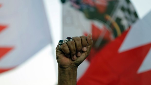 A Bahraini anti-government protester raises his fist amid national flags during a rally against the Formula 1 Bahrain Grand Prix in April.