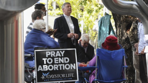 Catholic Archbishop of Canberra and Goulburn Christopher Prowse, centre, attends a prayer vigil outside the ACT Health building in Moore Street, Civic on Tuesday.