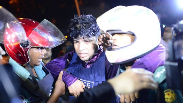An injured Bangladeshi policeman being assisted after the attack.