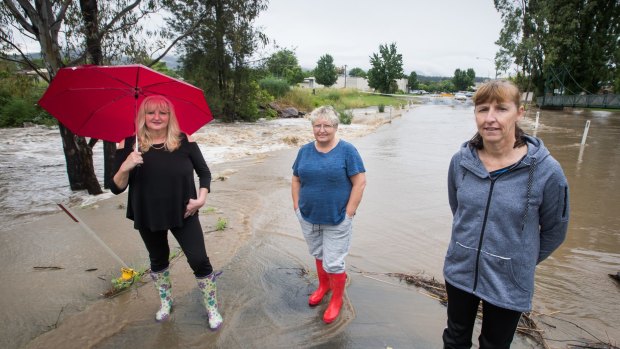 Sisters Jenni Harty, Kathy Moran and Annie Moran in flooded Standish Street, Myrtleford, on Saturday.