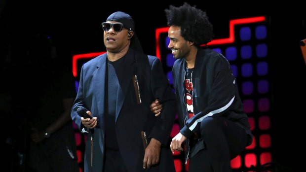 Stevie Wonder kneels on stage next to his son Kwame Morris before performing at the Global Citizen Festival in Central Park in New York.