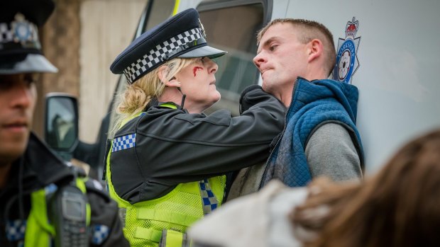  Catherine Cawood (Sarah Lancashire) pushes Jamie Dorrington against a police van in Happy Valley.