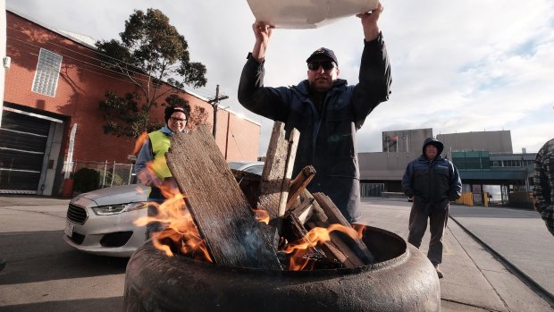 Sacked workers try to keep warm on the picket line.