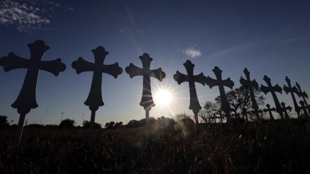The sun sets behind 26 crosses placed in a field before a vigil for the victims of the First Baptist Church shooting on Monday in Sutherland Springs, Texas. 