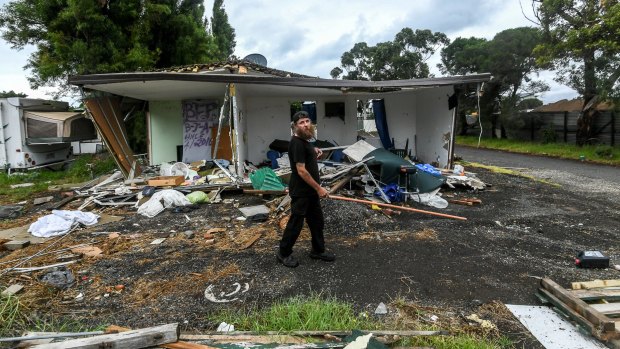 Hobsons Bay Caravan Park resident Michael walks past a trashed van that belonged to his neighbour. 