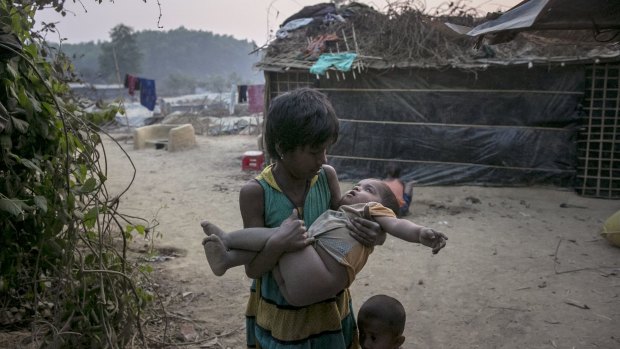 A girl carries a toddler in her arms in Kutapalong Rohingya refugee camp in Cox's Bazar, Bangladesh. 