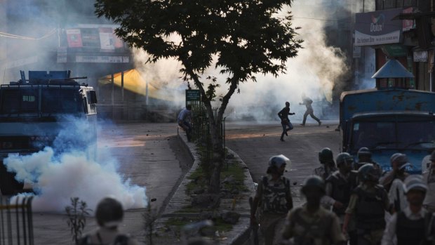 Kashmiri Muslim protesters run for cover from plumes of tear gas as Indian paramilitary soldiers walk back towards their base camp after a day-long curfew in Srinagar, Indian controlled Kashmir on August 8.