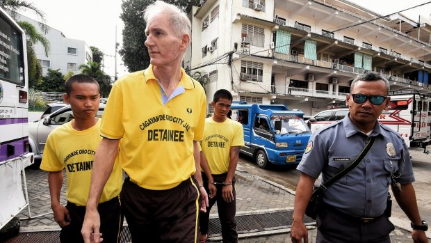 Peter Scully (second from left) arrives at the Cagayan de Oro court handcuffed to another inmate on the first day of his trial in September. 