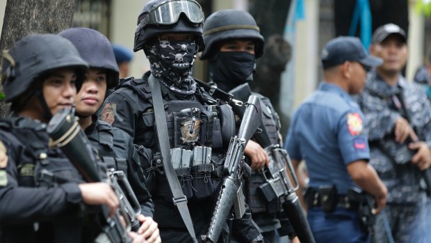Armed police keep watch as men suspected of being Marawi militants arrive at the Department of Justice in Manila, Philippines.