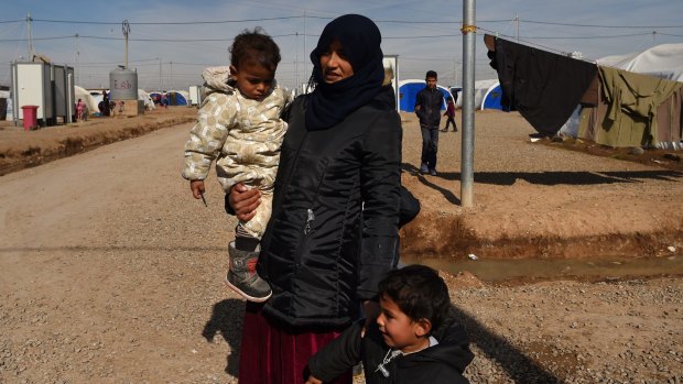 A woman walks with her two children inside Khazer Camp, home to tens of thousands who have fled ISIS.