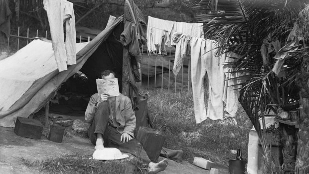 An unemployed man reads <i>How to End Capitalism</i> beneath drying washing in the Domain during the Great Depression, 1932.