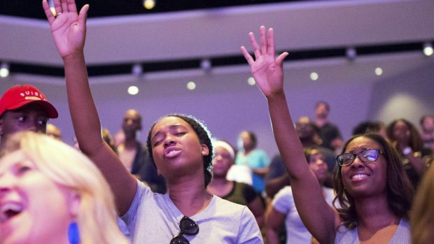 Allyson LaFrance and Amber Shields (right) raise their hands during a service at Concord Church in Dallas. 