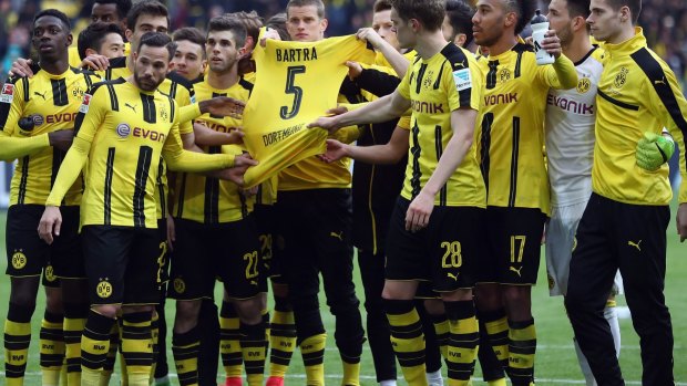 Players of Dortmund hold the jersey of their injured team mate Marc Bartra after winning the Bundesliga match between Borussia Dortmund and Eintracht Frankfurt.