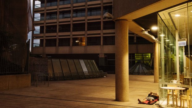 A man lays outside the State Library of New South Wales, in the background, the offices of New South Wales Parliament.