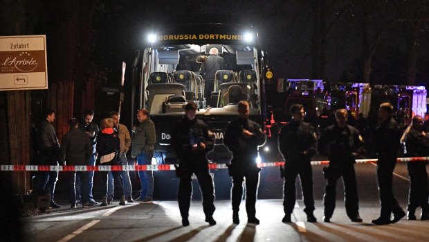 Police officers stand in front of Dortmund's damaged team bus.